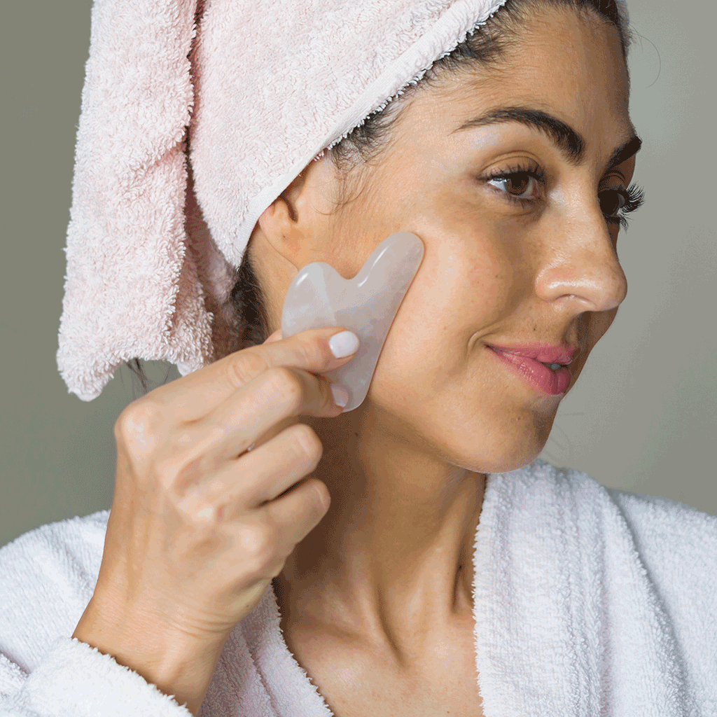 woman using gua sha on her face with JAVA Skin Care Face Serum